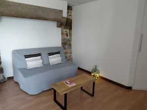 Una habitación con un sofá gris, una mesa de madera con una revista y una botella decorativa.