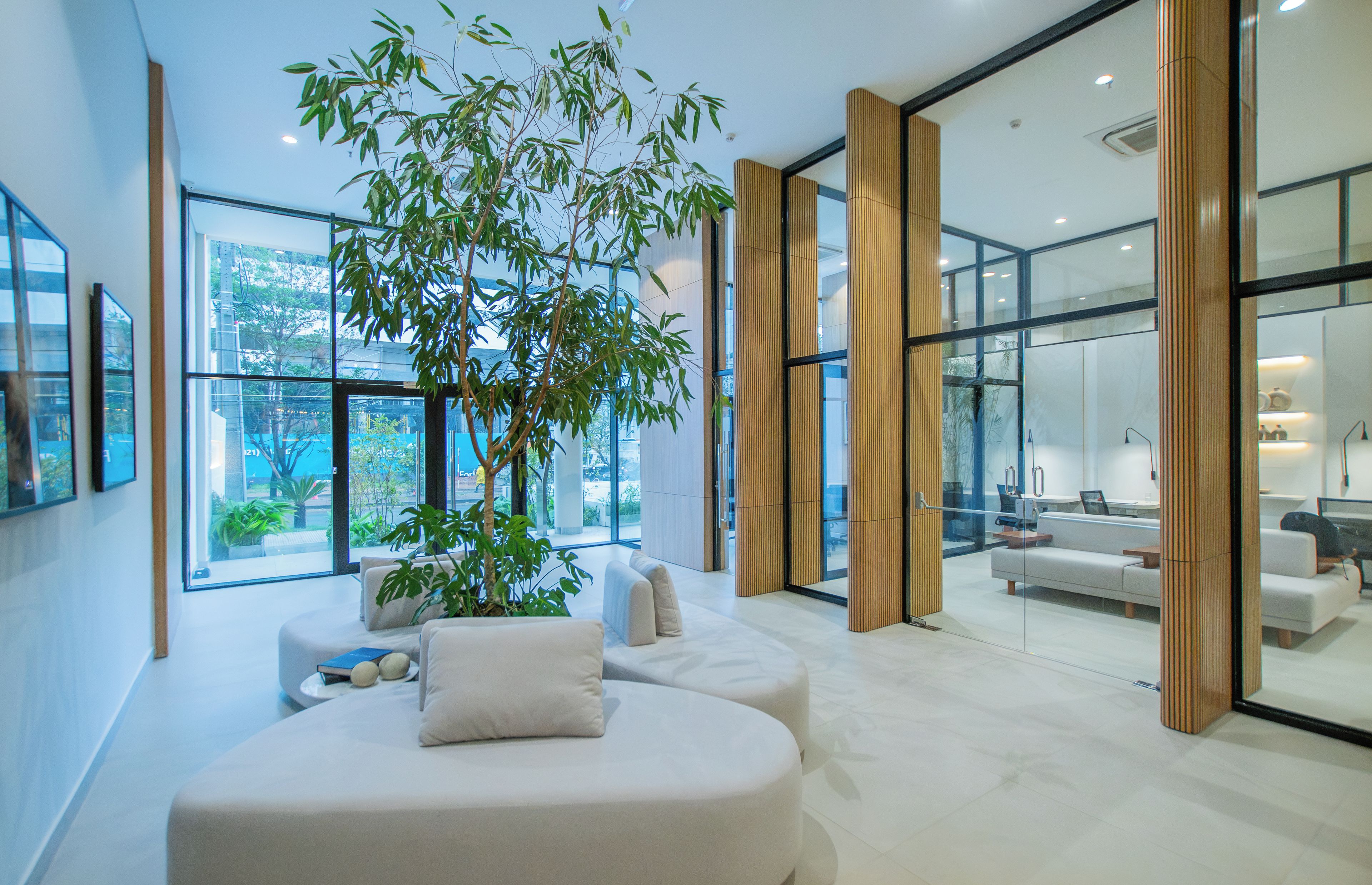Un interior moderno con un ventanal grande, un sofá, una planta y vistas al exterior.