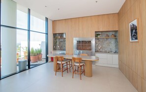 A modern kitchen with wooden cabinets, a dining table with chairs, and a large window. - Corporate Stays Habitalis Mburucuya- 15E (Asunción)
