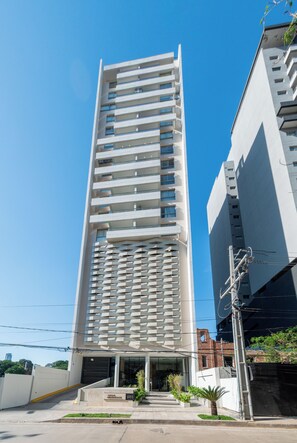 A modern high-rise building with a prominent entrance and a series of balconies. - Corporate Stays Habitalis Mburucuya- 15E (Asunción)