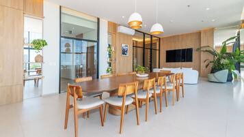 Un comedor moderno con una mesa y sillas de madera, un ventanal grande y un televisor de pantalla plana montado en la pared.