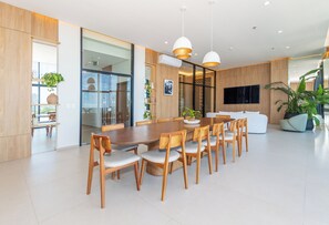 Ein moderner Essbereich mit Holztisch und Stühlen, einem großen Fenster und einem an der Wand befestigten Flachbildfernseher.