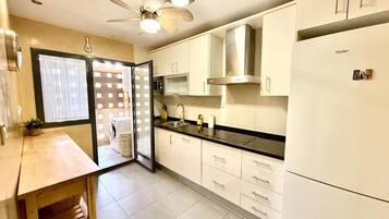 A modern kitchen with white cabinets, a black countertop, and a ceiling fan.