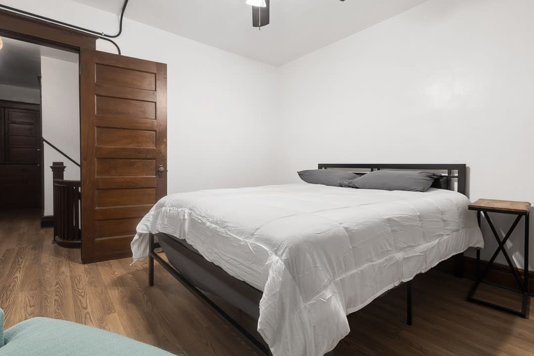 Una camera da letto con un letto, una porta in legno e un comodino.
