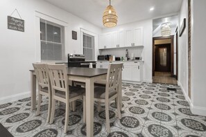 Una cucina moderna con mobili bianchi, un tavolo da pranzo con sedie e piastrelle a motivi.