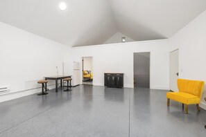 Une pièce spacieuse avec un plafond haut, une table à manger avec des chaises, une chaise jaune et un buffet.