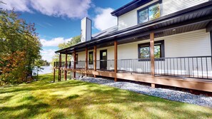 Ein zweistöckiges Haus mit einer Veranda und Blick auf einen See.