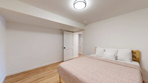 Ein Schlafzimmer mit einem Bett, einem Holzkopfteil und einer Tür zu einem anderen Raum.