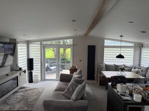 A modern living room with a sofa, a dining table, and a TV. - Ty Mawr Holiday Park Swift Toronto Lodge (Abergele)