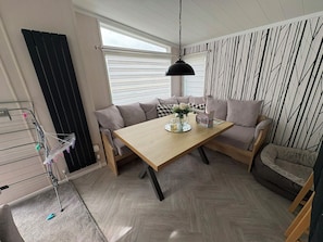 A cozy living room with a wooden table, a sofa, and a hanging light fixture. - Ty Mawr Holiday Park Swift Toronto Lodge (Abergele)