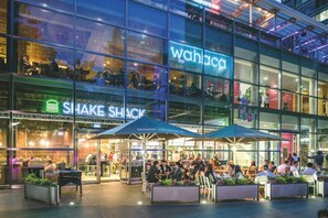 Een modern gebouw met een glazen gevel, een 'wahaca' restaurant en terrassen.