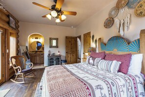 A bedroom with a large bed, wooden furniture, a ceiling fan, and decorative wall art. - Sundance Lodge in Angel Fire (Angel Fire)
