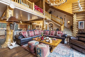 A spacious living room with a large sectional sofa, a wooden coffee table, and a staircase leading to an upper level. - Sundance Lodge in Angel Fire (Angel Fire)