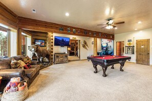 A cozy room with a pool table, a bear statue, and a television. - Sundance Lodge in Angel Fire (Angel Fire)