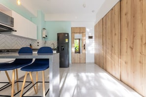 A modern kitchen with a central island, a refrigerator, and a dining area with blue chairs. - Utopía 2.West-StylishApt•OpticalFiber•Self CheckIn (Medellín)