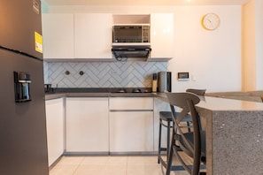 A compact kitchen with a microwave, coffee machine, and a clock on the wall. - Utopía 1.East-Calm Loft•Optical Fiber•SelfCheckIn (Medellín)