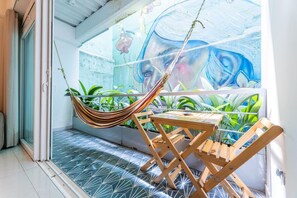 A hammock on a balcony with a view of a mural, potted plants, and a patterned floor. - Utopía 1.East-Calm Loft•Optical Fiber•SelfCheckIn (Medellín)