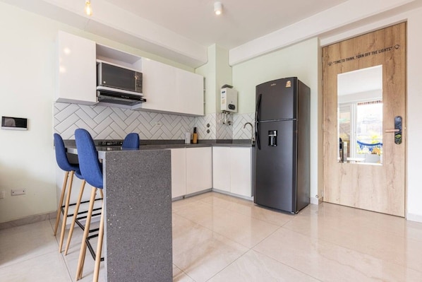 A modern kitchen with a microwave, refrigerator, and bar stools. - Utopía 4.West - Shining 2BR•Wi-Fi•AC•Self Check-In (Medellín)