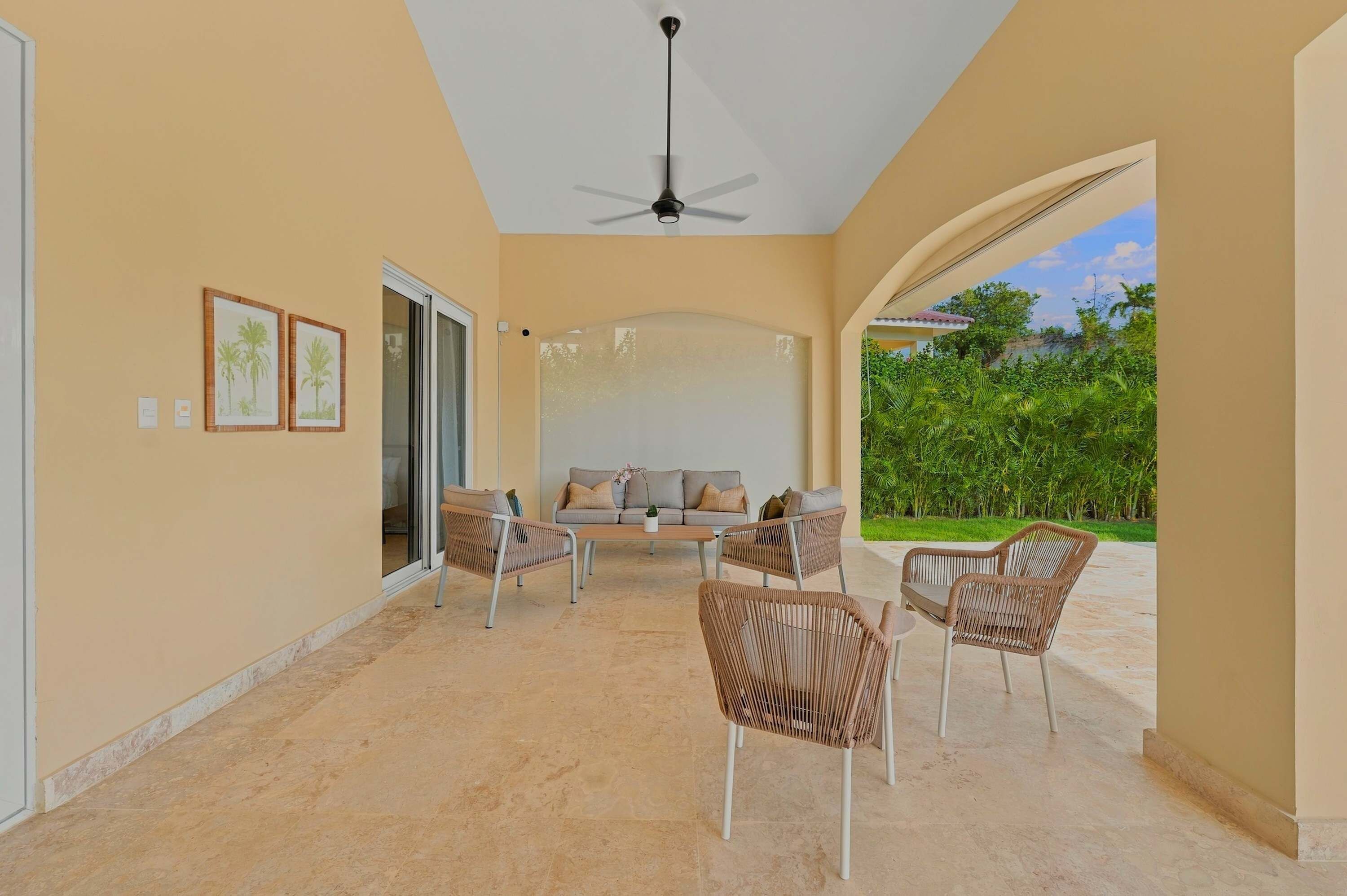 Une vaste terrasse dotée d’un ventilateur de plafond, d’un canapé et de fauteuils en osier.