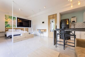 A modern hotel room with a bed, a TV, a desk, and a kitchen area. - Utopía 3.East-Charming Loft•Wi-Fi•AC•SelfCheck In (Medellín)