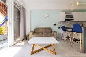 A modern living area with a sofa, a dining table, and a kitchen in the background. - Utopia 5.West - Bright 2BR•AC•Self Check-In•Wi-Fi (Medellín)