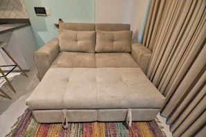 A beige sofa with a matching ottoman and a colorful striped rug. - Utopía M.East-Peacefull Loft•Wi-Fi•Self Check-In (Medellín)