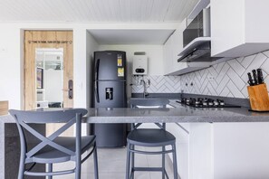 Una cucina moderna con isola integrata, elettrodomestici in acciaio inox e una parete di fondo rivestita con piastrelle a spina di pesce.