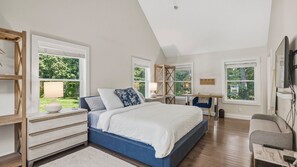 Ein Schlafzimmer mit einem Bett, Nachttischen, einem Schreibtisch und einem Sessel.
