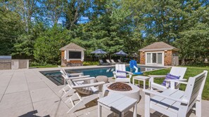 A backyard with a swimming pool, lounge chairs, a barbecue area, and two small wooden structures. - Private East Hampton Oasis with Heated Pool & hot tub, Modern Interiors,... (East Hampton)
