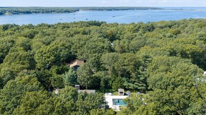 A residential area with a swimming pool, surrounded by dense forest, and a view of a large body of water with boats. - Private East Hampton Oasis with Heated Pool & hot tub, Modern Interiors,... (East Hampton)