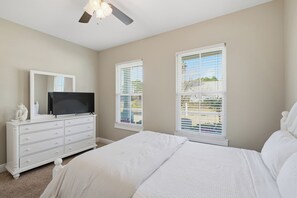 A bedroom with a bed, a dresser, a television, and a ceiling fan. - Free 6-Seater Golf Cart, Private Pool & Spa, Putting Green (Panama City Beach)