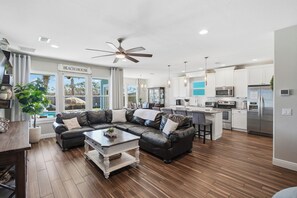 A modern kitchen with stainless steel appliances, a dining area with a leather sofa, and a large window offering a view of the outdoors. - Free 6-Seater Golf Cart, Private Pool & Spa, Putting Green (Panama City Beach)