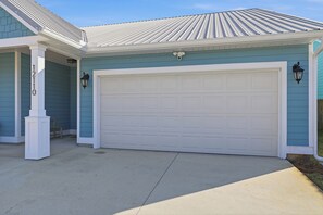 A residential garage with a white door, a light blue exterior, and a covered porch area. - Free 6-Seater Golf Cart, Private Pool & Spa, Putting Green (Panama City Beach)