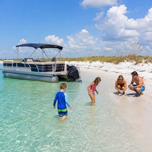 A beach scene with a boat, clear water, and people. - Free 6-Seater Golf Cart, Private Pool & Spa, Putting Green (Panama City Beach)