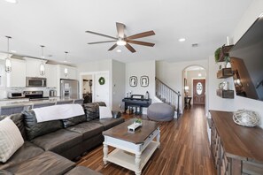 A modern living room with a leather sofa, a wooden coffee table, and a dining area with a kitchen in the background. - Free 6-Seater Golf Cart, Private Pool & Spa, Putting Green (Panama City Beach)