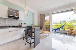 Eine moderne Küche mit Essbereich, einer Couch und einem Balkon mit einer Hängematte.