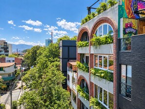 A multi-story building with a mix of brick and modern architecture, featuring balconies with greenery. - Utopia 5.East - Modern Loft•AC•Wi-Fi•Self Check-In (Medellín)