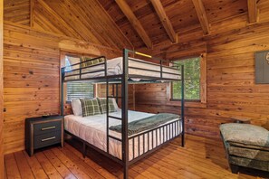 Une chambre avec un lit superposé, des murs en bois et une fenêtre.