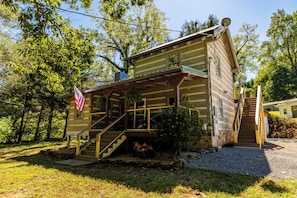 Eine Holzhütte mit Veranda, einer Flagge und einer Treppe zu einer zweiten Ebene.