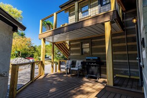 Une cabane en bois à deux étages, dotée d’une terrasse, de meubles de jardin et d’un barbecue.