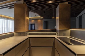 Una cocina moderna con electrodomésticos integrados, techo de madera y vista al salón.