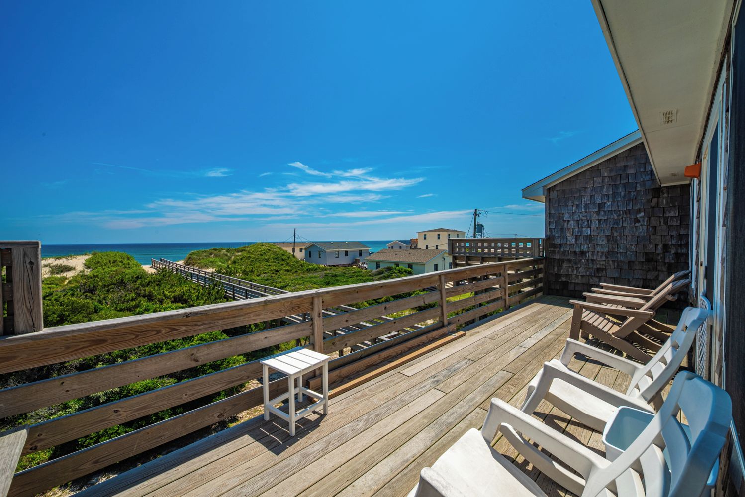 A wooden deck with a railing overlooking a beach and ocean.