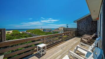 A wooden deck with a railing overlooking a beach and ocean.