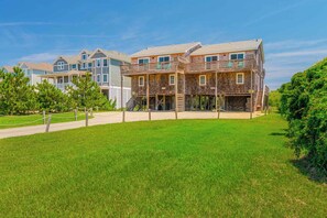 A row of modern multi-story buildings with balconies, a grassy lawn, and a clear sky. - JL #367-A Double Dare - Oceanfront - Hot Tub (South Nags Head)