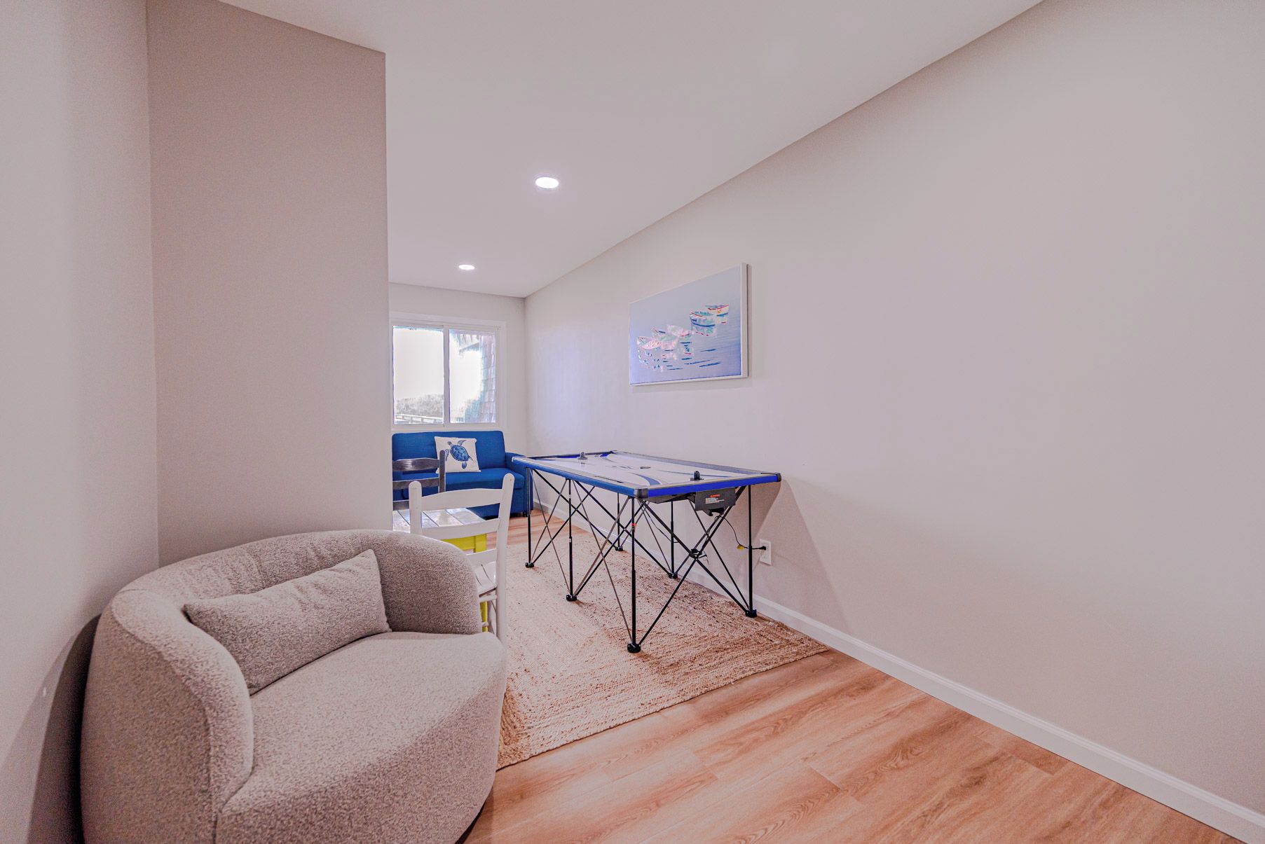A room with a blue table, a beige armchair, and a painting on the wall.