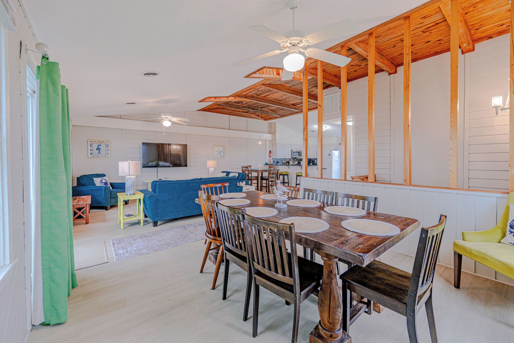 A spacious living area with a dining table, chairs, and a kitchen in the background.