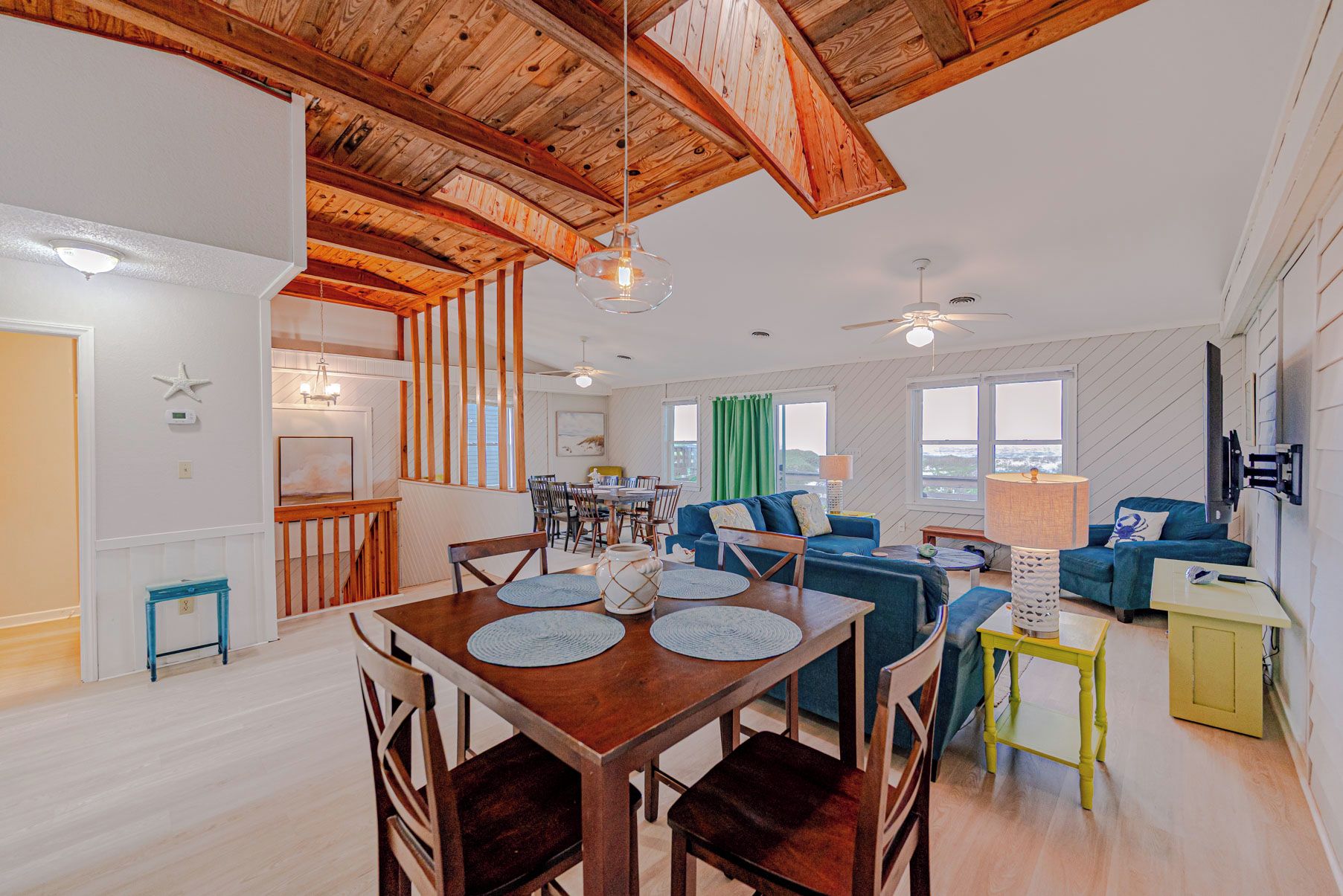A spacious living area with a wooden ceiling, a dining table with chairs, and a sofa.