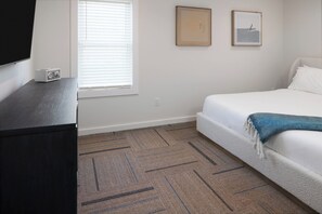 Ein Schlafzimmer mit einem Bett, einem Fernseher und einem Fenster mit Jalousien.