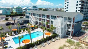 Ein Hotel mit Schwimmbad, Außenbereich zum Sitzen und einem Parkplatz.
