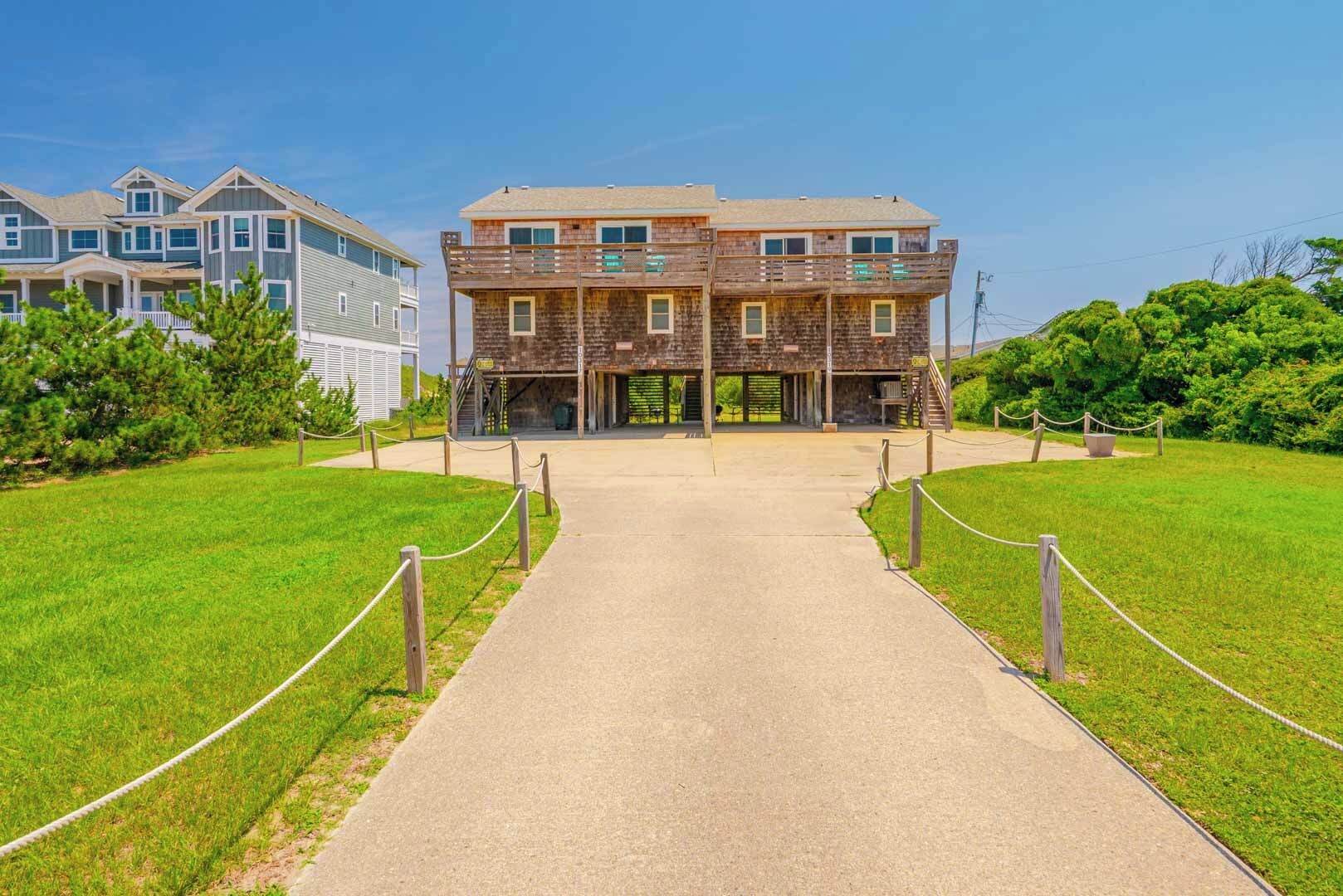 A two-story building with a central entrance, surrounded by a grassy area and a pathway leading to it.